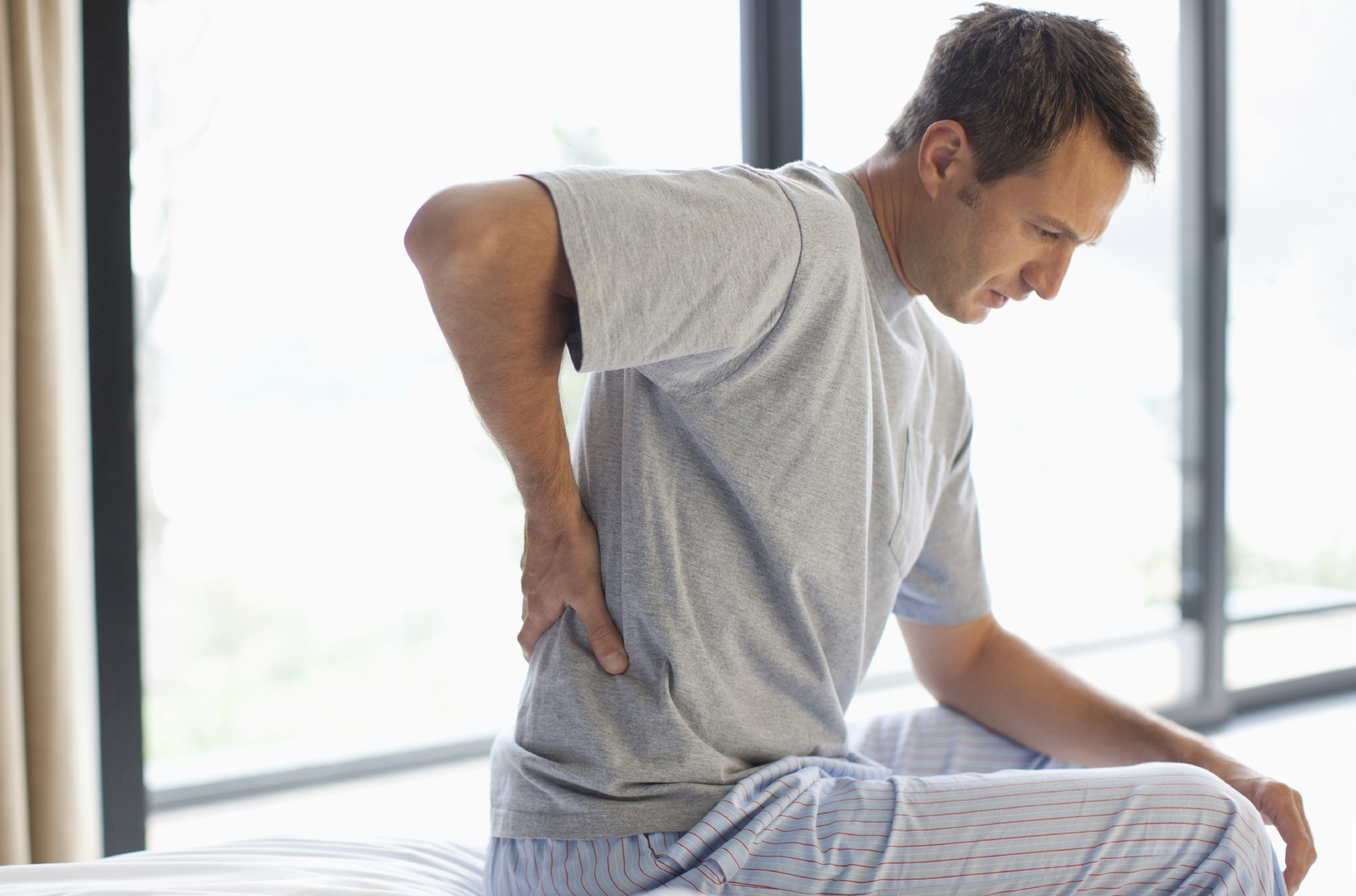 Man sitting on bed with backache